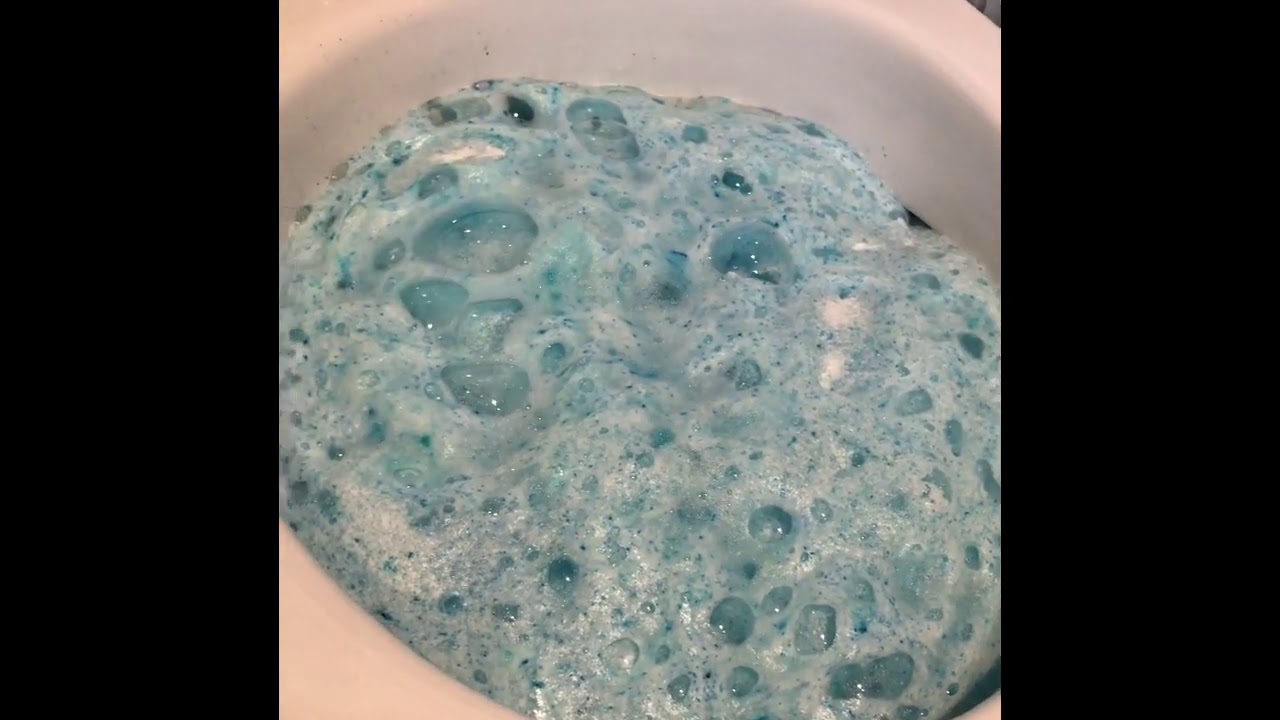 Weißes Keramik Wc mit hellblauen Schaum vom WC Pulver bis unter dem Rand